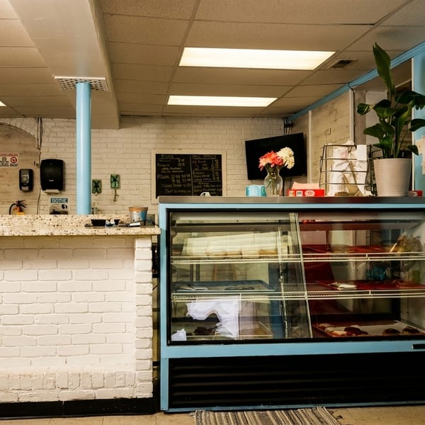 Interior of a casual restaurant with a display case, snack rack, and beverage cooler.