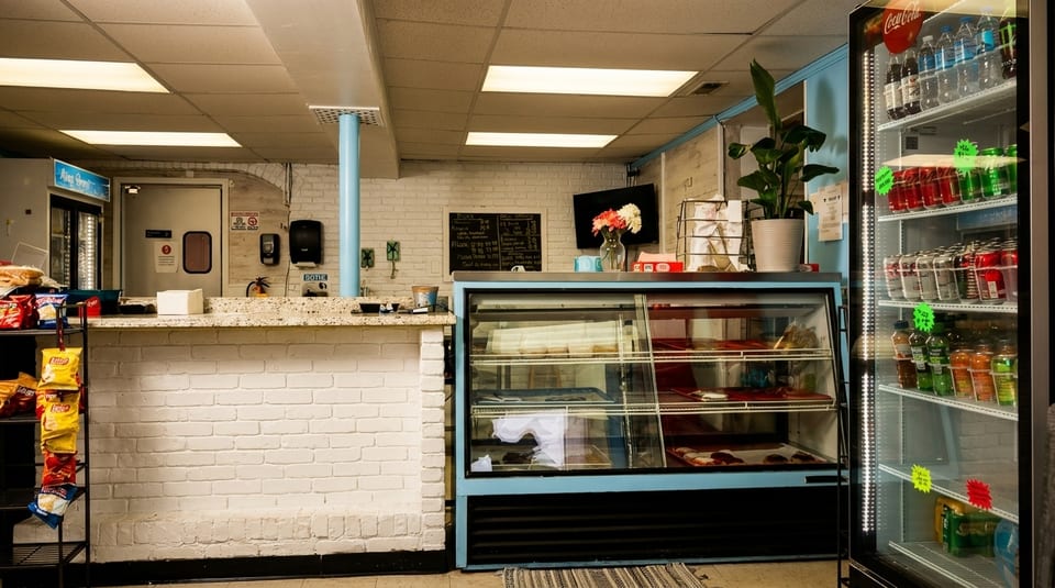 Interior of a casual restaurant with a display case, snack rack, and beverage cooler.