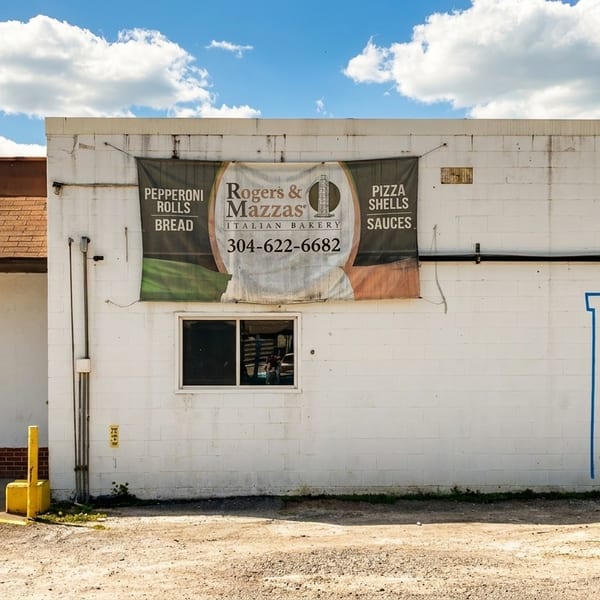Exterior of Rogers & Mazzas Italian Bakery, a white building with an Italian flag banner and a window.